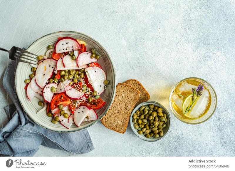 Gemüsesalat mit Bio-Tomaten und Kapern, Limonade und Brot Schalen & Schüsseln konserviert Kapriolen Kapparis Küche Abendessen Lebensmittel frisch Glas grün