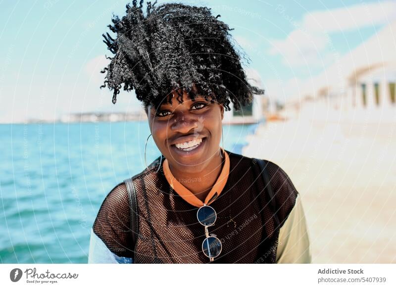 Charmante schwarze Frau auf dem Deich in der Stadt Strandpromenade Hafengebiet genießen sich[Akk] entspannen sonnig Afro-Look Frisur charmant Lächeln ethnisch