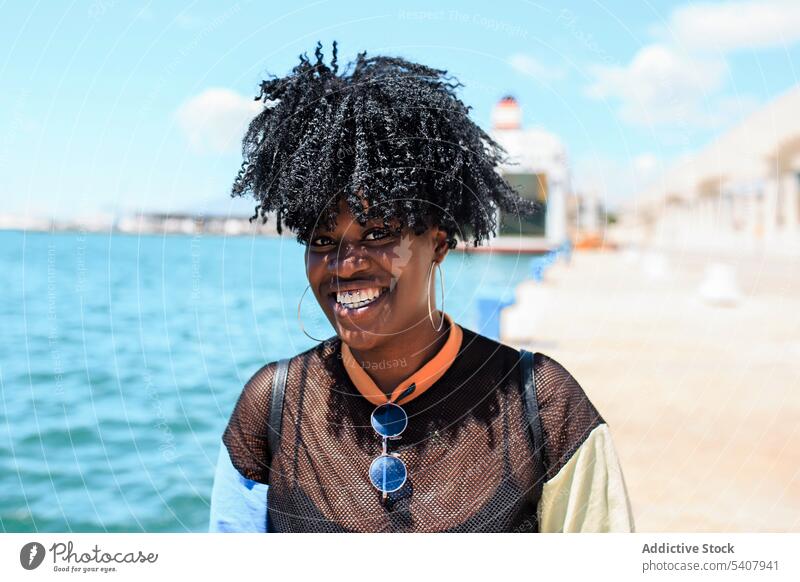 Charmante schwarze Frau auf dem Deich in der Stadt Strandpromenade Hafengebiet genießen sich[Akk] entspannen sonnig Afro-Look Frisur charmant Lächeln ethnisch