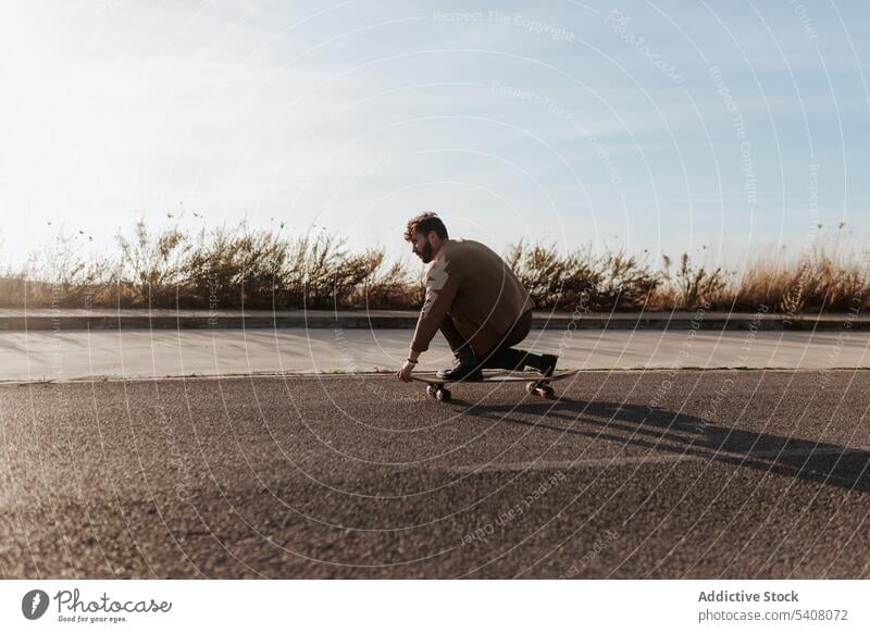 Trendiger Skater, der auf einer Landstraße einen Trick vorführt Mann ausführen Straße Landschaft Natur ländlich Asphalt berühren Boden Fähigkeit Talent männlich