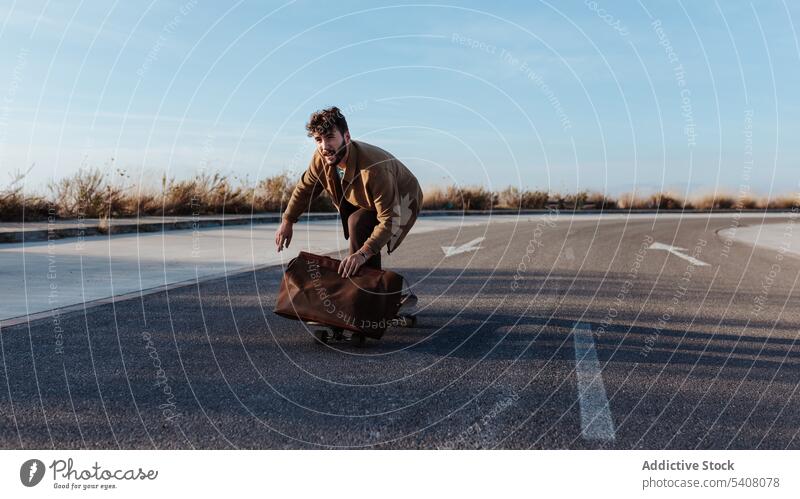 Junger bärtiger Skater mit Tasche fährt auf der Straße Mann Longboard Fähigkeit Mode Stil Skateboard Asphalt Mitfahrgelegenheit Hobby Aktivität männlich