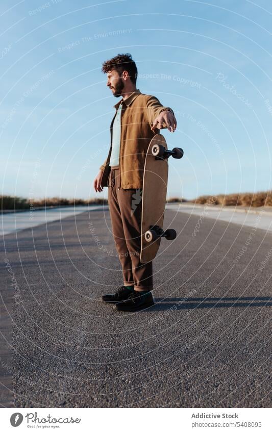 Bärtiger Skater wirft Skateboard auf Straße Mann Landschaft werfen Longboard ernst Hobby fallen cool Trick Fähigkeit männlich Aktivität ländlich Asphalt