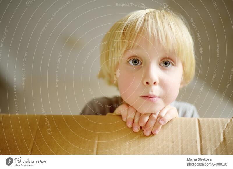 Niedlicher Vorschuljunge spielt in einem Karton während des Umzugs der Familie in ein neues Haus. Kinder spielen ist ein Weg zur Entwicklung kreativer Fähigkeiten.