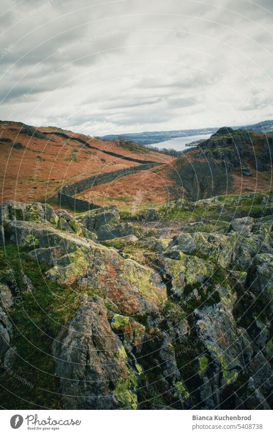 Blick von steiniger Landschaft hin zu einem Steinmäuerchen welches zu einem See am Horizont führt Außenaufnahme Farbfoto Menschenleer Umwelt Steine Steinmauer