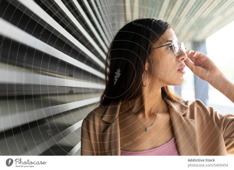 Stilvolle Frau in der Nähe der grauen Wand Geschäftsfrau Unternehmer Haare berühren formal Brille Accessoire Vorschein Business Outfit nahöstlich professionell