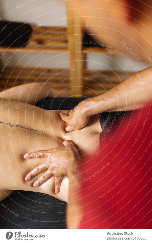 Unbekannter Masseur trägt Öl auf den tätowierten Rücken einer anonymen Frau bei Tag auf Klient Massage bewerben drücken Tisch Spezialist Salon männlich