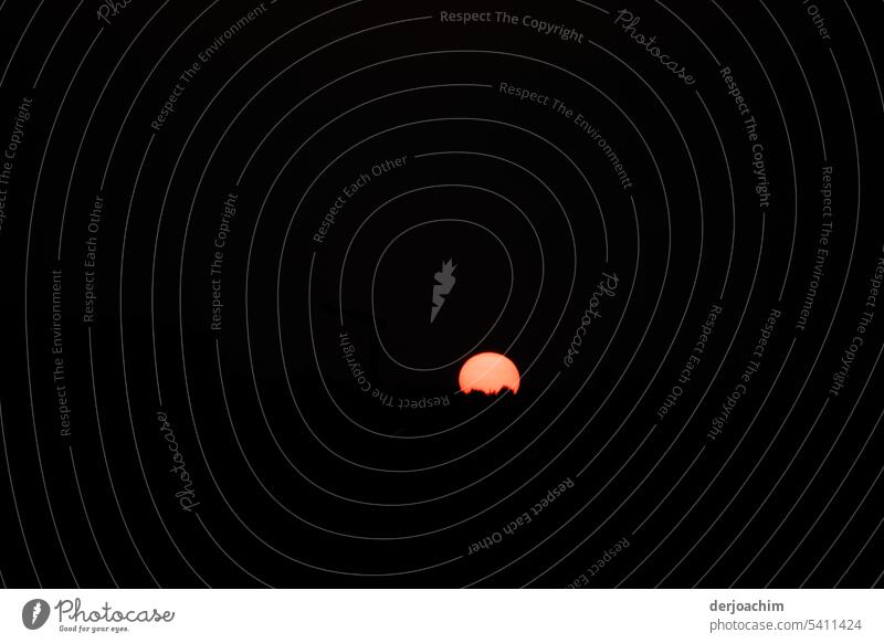 In fast  totaler Dunkelheit, die Sonne wie von einer Wolke gehalten, als Silhouette. Sonnenuntergang am Abend Himmel Außenaufnahme Horizont Menschenleer Licht