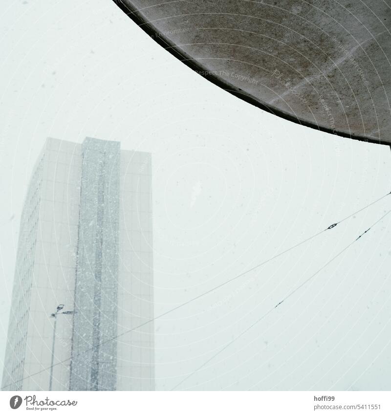 Schneetreiben in der Stadt mit Hochhaus, Oberleitung und runder Überdachung Schneefall kalt Schneeflocke schneetreiben urban Winterstimmung schlechtes Wetter