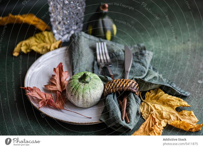 Herbstlich gedeckter Tisch vor dunklem Hintergrund herbstlich Einstellung Kulisse Besteck Gabel Messer Serviette Teller Tischwäsche Geschirr Blatt farbenfroh