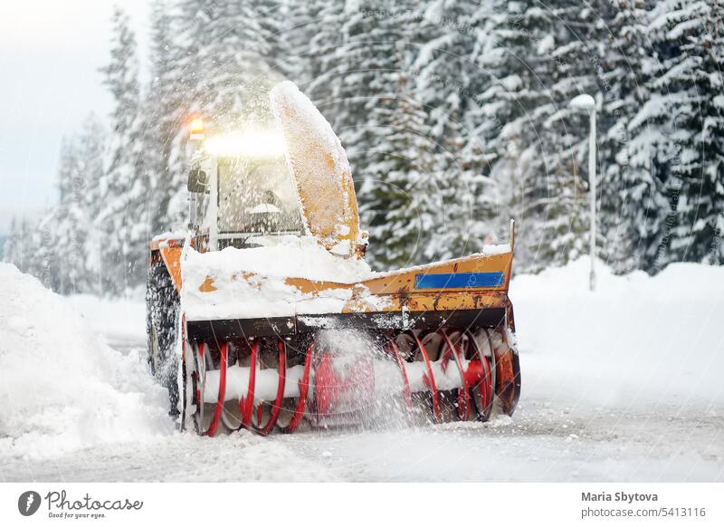 Ein Schneepflug räumt eine schneebedeckte Straße in den europäischen Alpen während eines Schneesturms. Verwehungen und Schneeverwehungen während eines Schneesturms.