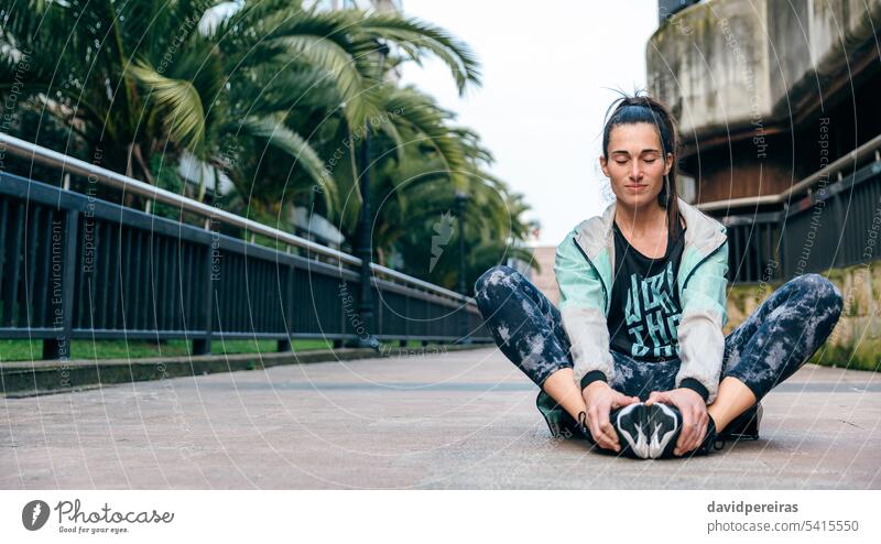 Läuferin mit geschlossenen Augen entspannt auf dem Boden sitzend nach dem Training Frau aussruhen entspannend sich[Akk] entspannen Pause Meditation zugeklappt