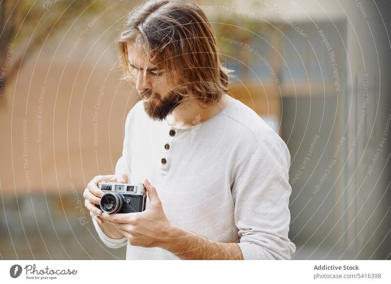 Gut aussehender Mann, der die Kamera in der Hand hält gutaussehend fotografierend schwarz besinnlich Fotograf Schnurrbart Fotokamera Bartstoppel Erwachsener Hut