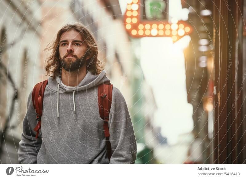 Hübscher Mann auf der Straße Frisur Rucksack Schnurrbart Kapuzenpulli Erwachsener gutaussehend Lifestyle Bartstoppel Fröhlichkeit bärtig Model jung