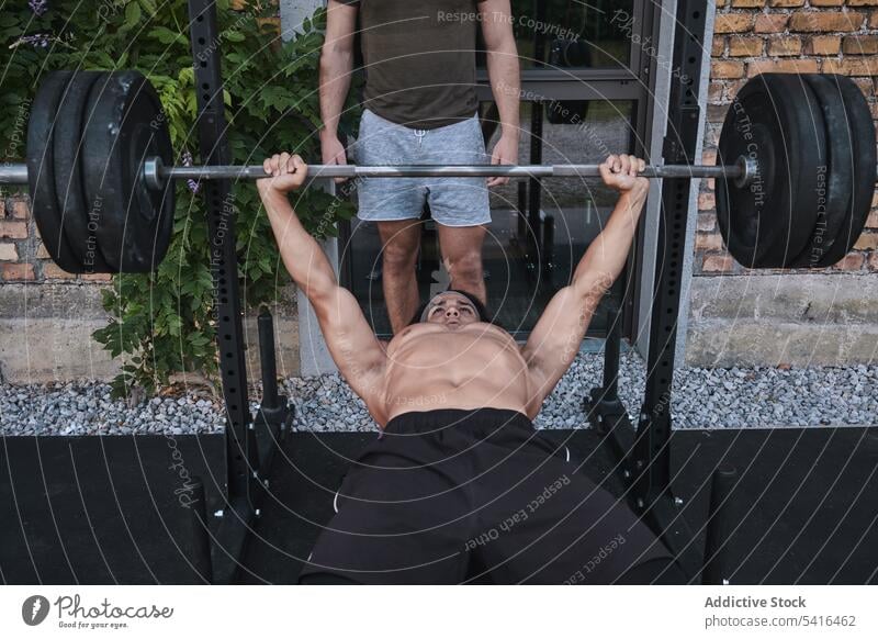 Ethnischer Mann hebt Langhantel mit Trainer Athlet Afrikanisch schwarz Amerikaner ohne Hemd Heben Curl-Hantel Trainerin Fitnessstudio männlich hispanisch Sport