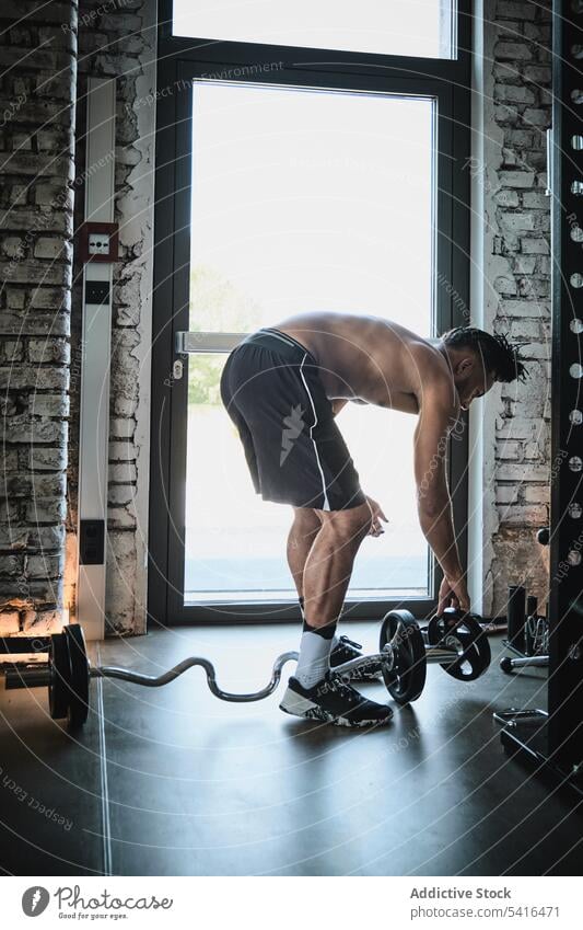 Schwarzer Mann trainiert mit Langhantel im Fitnessstudio Afrikanisch Amerikaner schwarz Heben Curl-Hantel ohne Hemd Training Übung Gewicht männlich passen stark