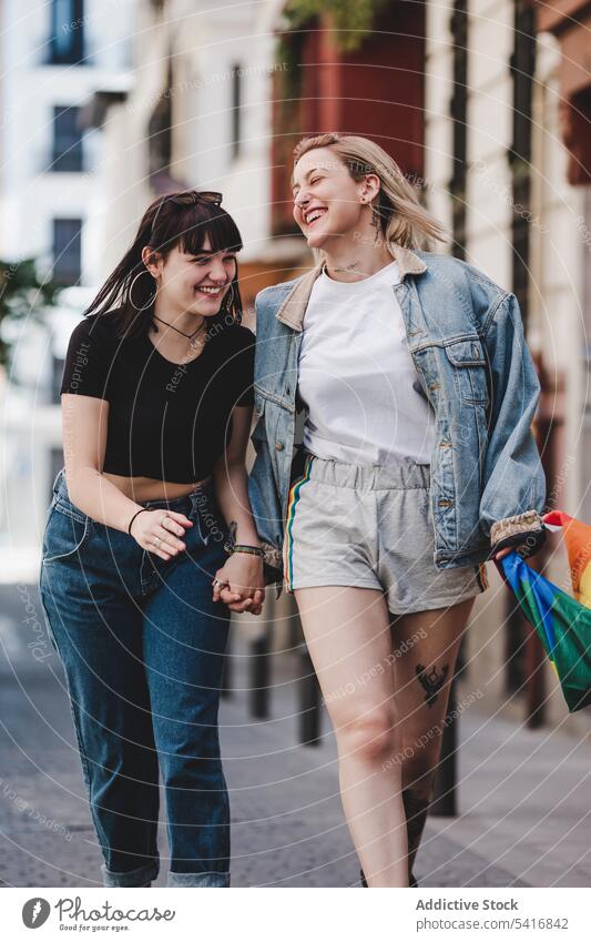 Lesbisches Paar mit LGBT-Flagge auf der Straße lesbisch Fahne lgbt laufen Glück winkend Großstadt jung Zusammensein Frauen lässig Homosexualität Stolz