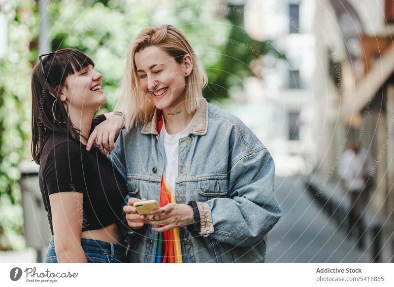 Lesbisches Paar telefoniert auf der Straße lesbisch Smartphone lgbt Glück Großstadt jung Zusammensein Frauen lässig Homosexualität Stolz Gleichstellung