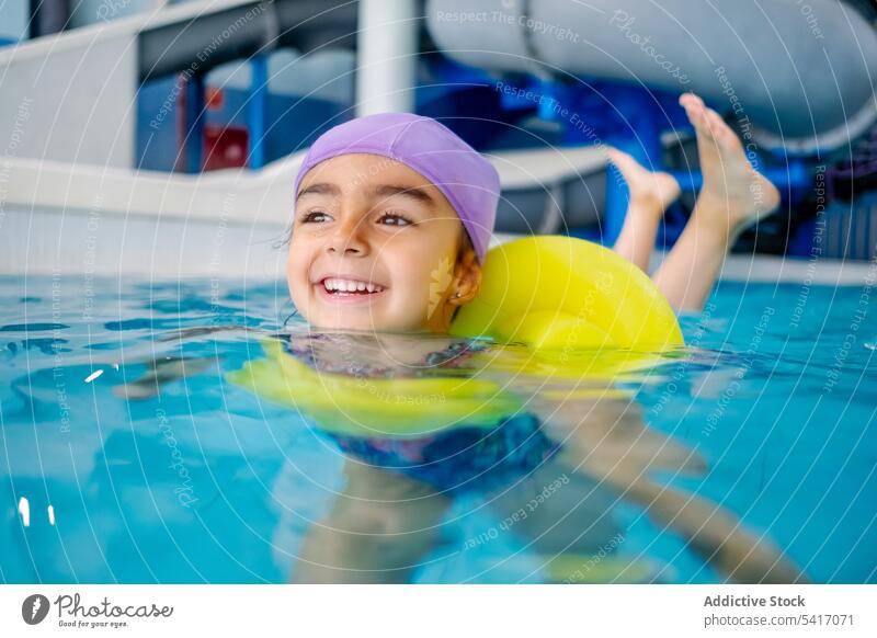 Ethnisches Mädchen mit Schwimmflügeln im Schwimmbad Spielen Wasser Park Schwimmsport Pool aufblasbar Flügel ethnisch Spielzeug Spaß Kind Freude Glück wenig