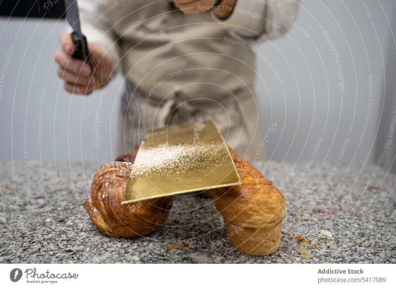 Zuckerbäcker, die Brötchen mit Puderzucker verzieren Mann Sieben Gebäck Essen zubereiten Pulver Dessert Dekoration & Verzierung Konditor Beruf Arbeit Teigwaren