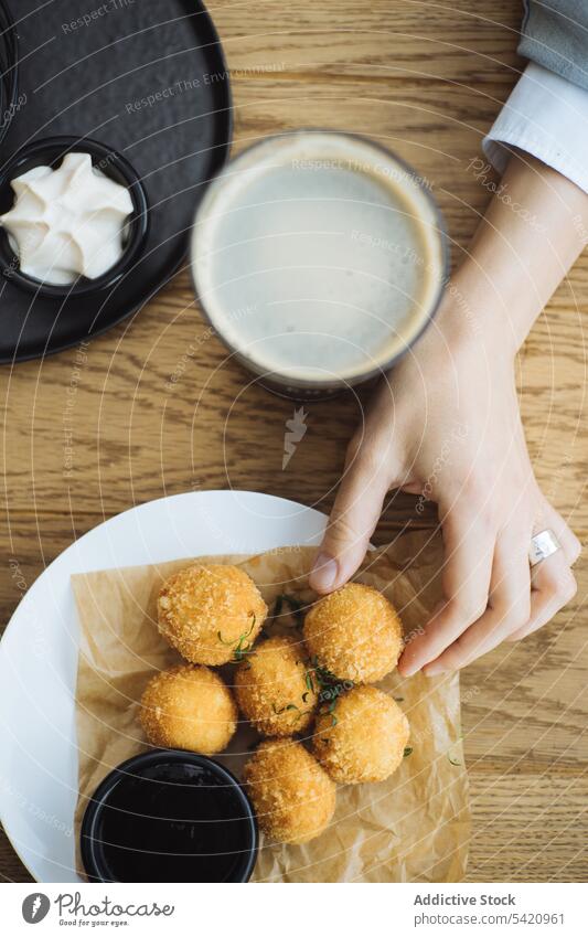 Frau isst Kartoffelkrokette am Tisch Krokette Ball gebraten essen Hand Lebensmittel knirschen Trödel lecker Snack geschmackvoll Teller Mahlzeit Küche Speise