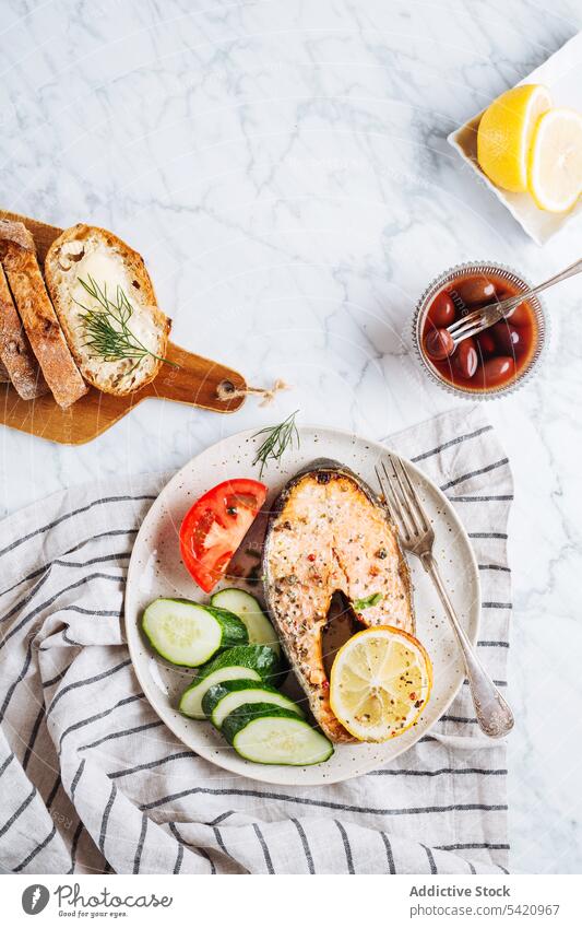 Gesundes Gericht mit Fisch und Gemüse Steak Lachs Salatbeilage Gesundheit Speise Teller dienen Abendessen Grillrost Lebensmittel Salatgurke Tomate Zitrone Kraut