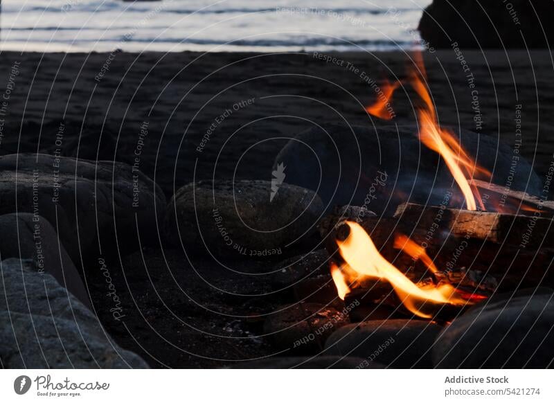 Brennendes Lagerfeuer am Ufer in der Abendzeit Seeküste Stein Feuer Freudenfeuer Flamme dunkel Wasser MEER Meer ruhig Brandwunde Strand sich[Akk] entspannen