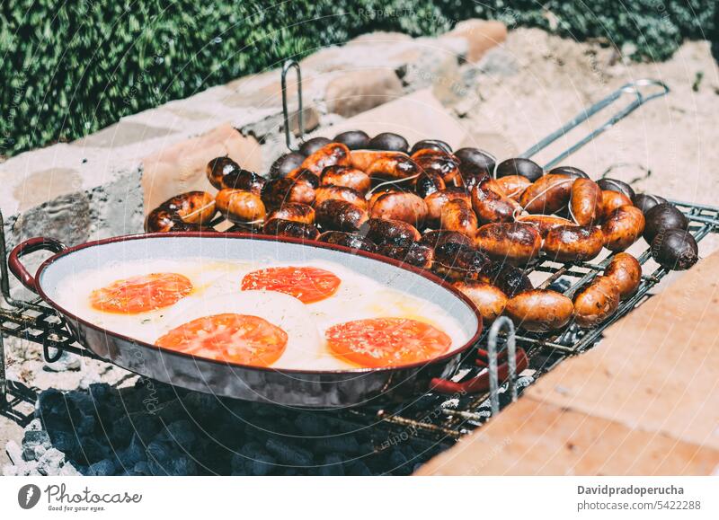 Chourizo und Provolone-Käse im Grill gebraten Barbecue chourizo gegrillt zerlaufen Fleisch Tomaten Tier Holzkohle Kohle Lebensmittel grillen Essen zubereiten