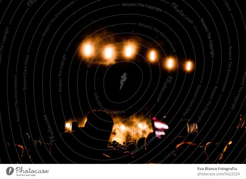 Bild von vielen Menschen, die sich an nächtlichen Aufführungen erfreuen, große, nicht wiedererkennbare Menschenmenge, die mit erhobenen Händen und Mobiltelefonen im Konzert tanzt. Nachtleben