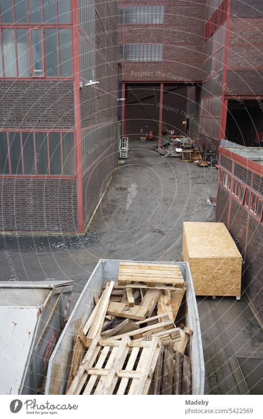 Mit weißen Tüchern kunstvoll verhangener Bauzaun am Sanierungsarbeiten mit Baucontainer und Holzpaletten am Schacht XII der Zeche Zollverein in Essen im Ruhrgebiet in Nordrhein-Westfalen in Deutschland