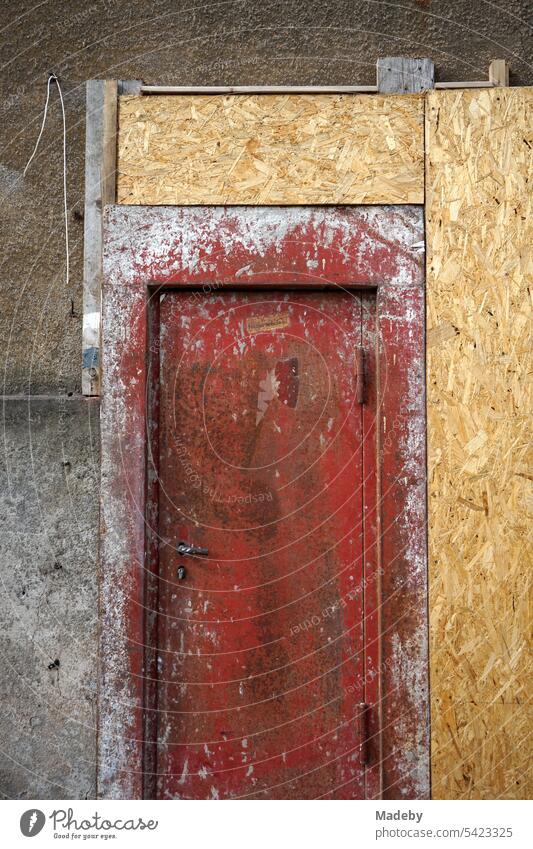 Brandschutztür in einer alter heruntergekommenen Fassade mit provisorischen Spanplatten in Naturfarben eines Altbau in Detmold am Teutoburger Wald in Ostwestfalen-Lippe