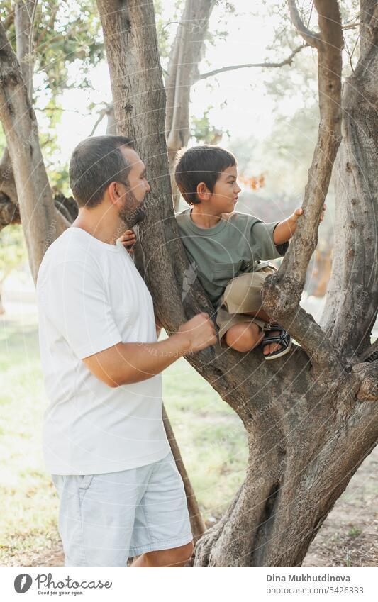 Vatertag. Papa mit Sohn im Sommer Park Klettern Baum, Spaß haben. Glückliche Kindheit Aktivität. Vater und Sohn Bindung, die Qualität der Zeit zusammen. Mann