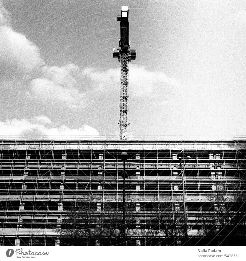 Kran und entkerntes Haus analog Analogfoto sw schwarzweiß Baustelle Architektur Gebäude Sanierung Umbau Außenaufnahme Laterne Gerüst Bauen