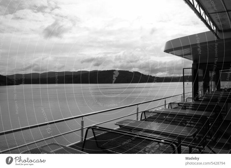 Tische und Bänke auf dem Deck eines Ausflugsschiff mit Blick auf den Edersee bei Waldeck im Landkreis Waldeck-Frankenberg in Hessen in neorealistischem Schwarzweiß