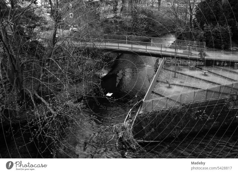 Blick aus der Wuppertaler Schwebebahn auf Eineinen kleinen Park mit Brücke für Fußgänger in Wuppertal an der Wupper im Bergischen Land in Nordrhein-Westfalen in neorealistischem Schwarzweiß