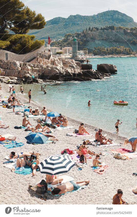 Badegäste am Bestouan Strand von Cassis mit Leuchtturm im Hintergrund Mittelmeer Strang Sonnenschirme Urlauber Plage du Bestouan Kiesstrand klares Wasser türkis