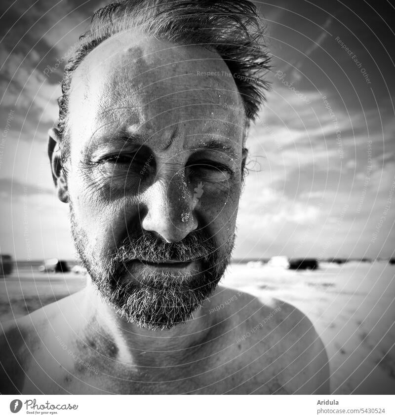 Portrait | Mann am Strand s/w Porträt Wind Gesicht Bart Mensch Blick Kopf Erwachsene Blick in die Kamera Falten freier Oberkörper Sonnenlicht Kontrast maskulin