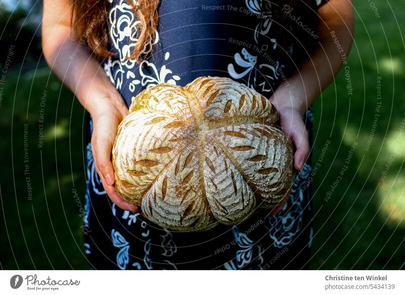 ein schön verziertes Brot in den Händen einer jungen Frau selbstgebackenes Brot unser täglich Brot Brotlaib Wärme saftig rund Grundnahrungsmittel Geschmack