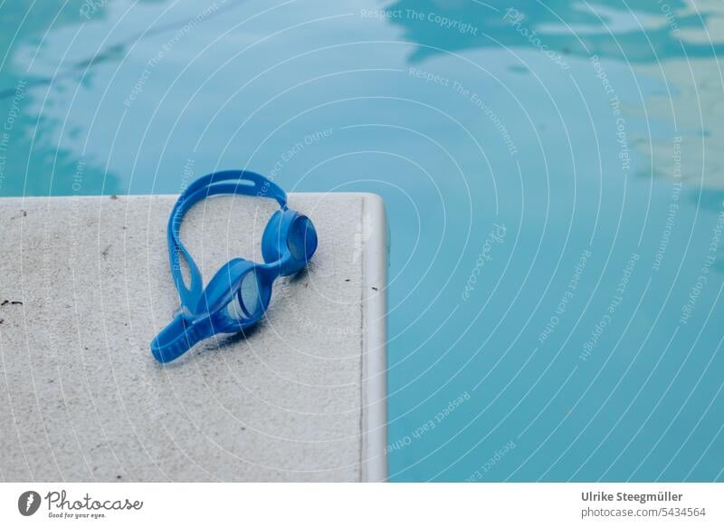 Eine blaue Taucherbrille liegt auf einem weissen Sprungbrett am blauen Pool Sommerurlaub schwimmen tauchen Kinder Urlaub mit Kindern schwimmen lernen