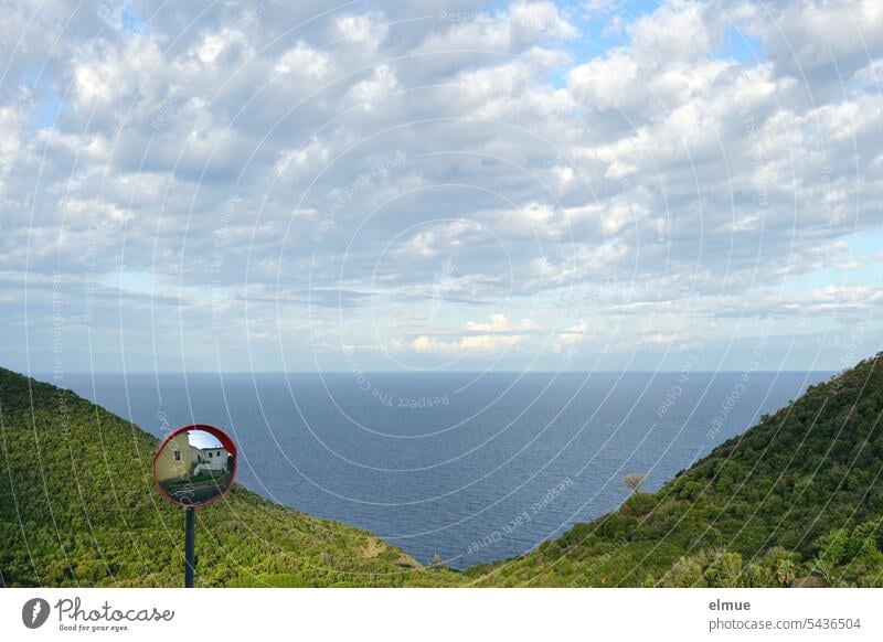 Blick von Elba aus auf Korsika über einen Verkehrsspiegel, das Mittelmeer und bewaldete Hügel hinweg Italien Ferien & Urlaub & Reisen Insel italienische Insel