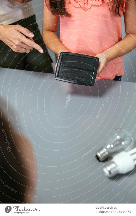 Eine Schülerin zeigt einem Klassenkameraden im Ökologieunterricht ein Solarpanel unkenntlich Frau zeigend Panel solar Schulmädchen Klassenraum Lehrer