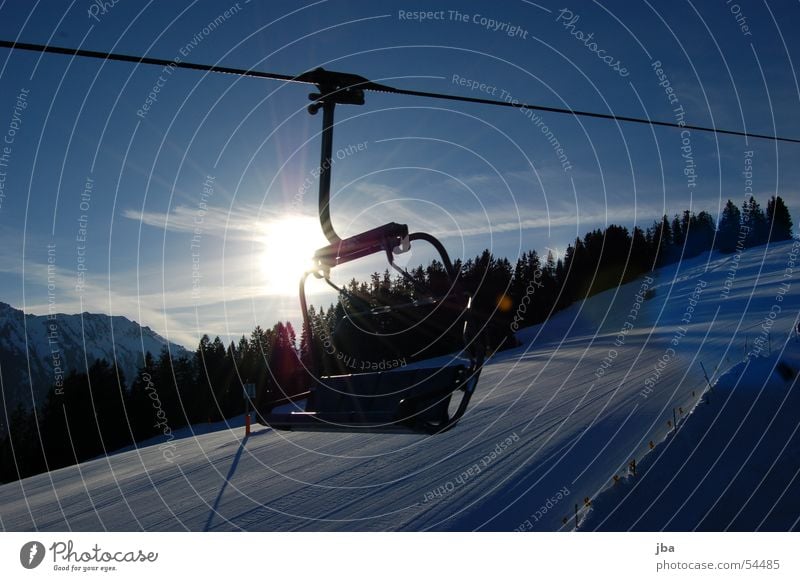 Sessel im Gegenlicht Sesselbahn fahren Haken Winter Sonnenaufgang Wald kalt Kunstschnee Gstaad Saanenland Sitzgelegenheit Seil sitzen Schnee Himmel