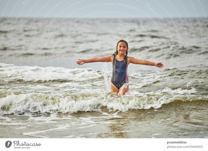 Kleines Mädchen spielt mit Wellen im Meer. Kind plantscht spielerisch in Wellen. Kind springt ins Meer. Urlaub am Strand. Wasser plätschert Sommer Ferien MEER