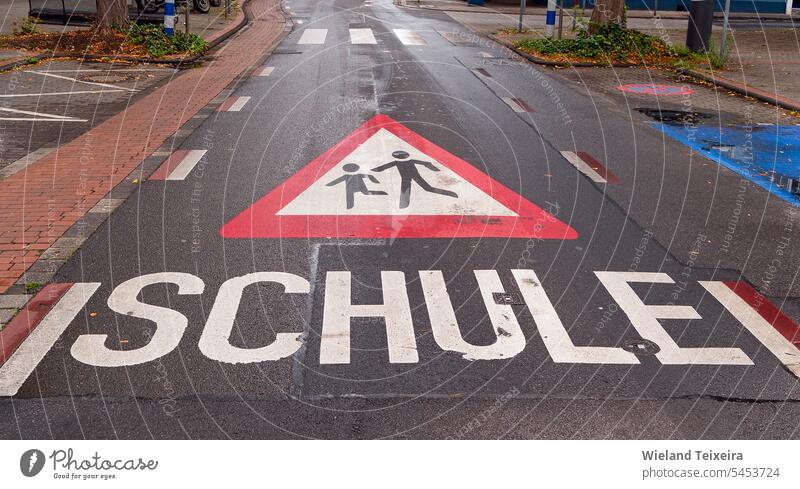 Auf den Asphalt gemaltes Warnschild für spielende Kinder. Dieses Schild stand in der Nähe einer Schule Kinder beim Spielen Straßennamenschild Uhr für Kinder