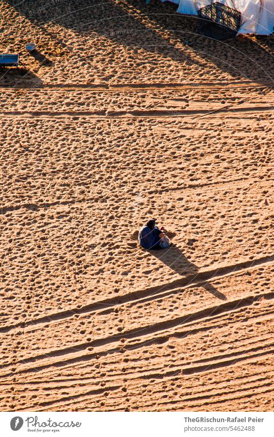 Frau sitzt am Boden und arbeitet in der Wüste Sand Außenaufnahme Farbfoto Natur Sonne Tourismus Wahiba Sands Oman omanische Wüste Landschaft