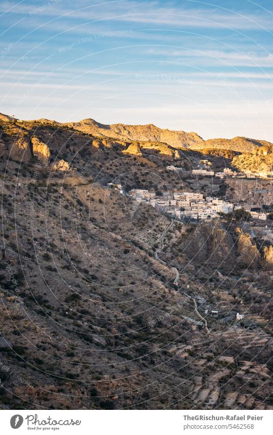 Kleines Dorf inmitten von Bergen im Sonnenuntergang Oman steil hügelig Stimmung Straße Jebel Akhdar trocken heiß Natur Farbfoto Himmel Tourismus Arabien Tag