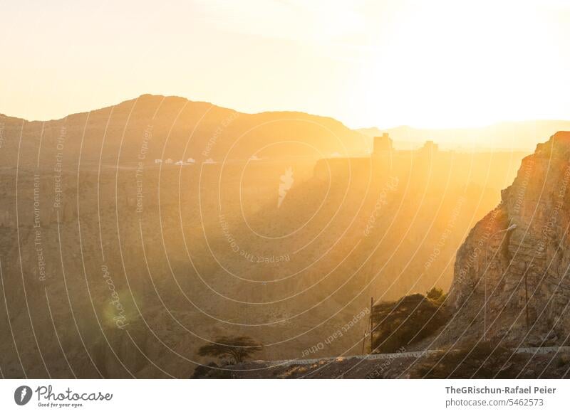 Panorama von Sonnenuntergang inmitten von Bergen mit Schloss im Hintergrund Oman steil hügelig Stimmung Jebel Akhdar trocken heiß Natur Farbfoto Himmel