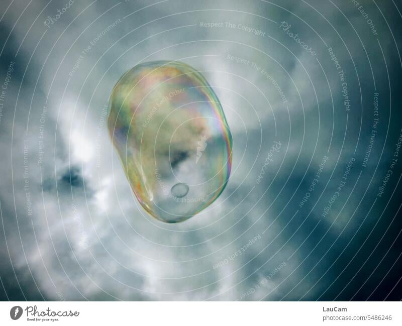 Kontrastreich - bunte Seifenblase vor düsterem Himmel dunkler Himmel Wolken grau kontrastreich fliegen schimmern schimmernd Schweben Luft Leichtigkeit glänzend