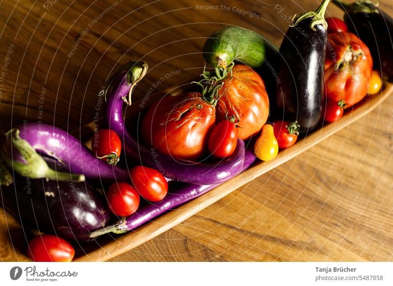 Frische Auberginen und Tomaten - bunte Vielfalt in einer Holzschale Bio-Gemüse längliche Auberginen gelbe Tomaten erntefrisch Bioprodukte lila rot grün