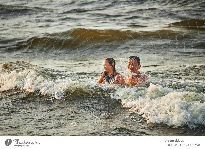 Kleines Mädchen und ihr Vater spielen mit Wellen im Meer. Sommerurlaub mit der Familie. Kind plantscht spielerisch mit Wellen. Sommerurlaub am Strand Ferien