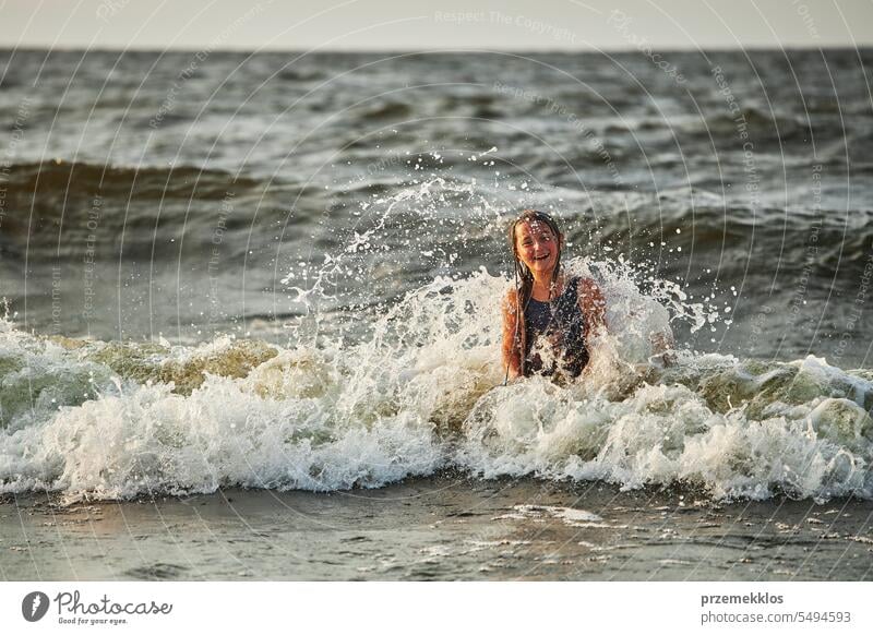 Kleines Mädchen spielt mit Wellen im Meer. Kind plantscht spielerisch mit Wellen. Kind springt in Meereswellen. Sommerurlaub am Strand Ferien MEER Spielen